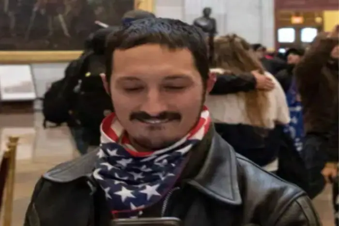 An image from the Metropolitan Police showing a man with a goatee looking at his phone in the Capitol Rotunda, with a stars and stripe bandana